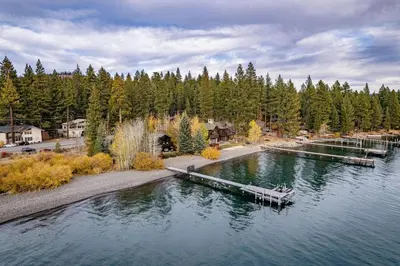 a dock in the water with a boat in it at Aqua Vista Lakefront Estate by Tahoe Getaways - 6 BR in Carnelian Bay w Buoy, Pier & Game Room in Carnelian Bay