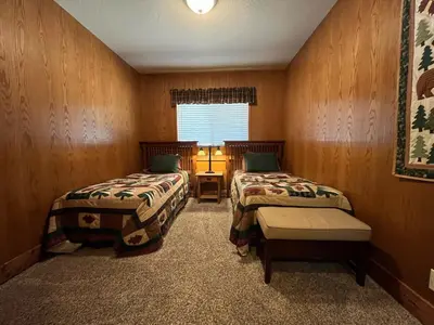 two beds in a room with wooden walls and a window at The Tree House II in Wawona