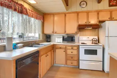 a kitchen with wooden cabinets and white appliances at Spindler's Chalet in Wawona