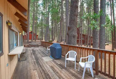 a wooden deck with two chairs and a tent on it at Spindler's Chalet in Wawona