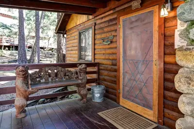 a porch of a log cabin with a bench and a door at Mia Mora in Wawona