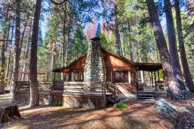 a log cabin in the middle of a forest at Creekside Cabin in Wawona
