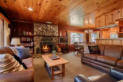 a living room with couches and a stone fireplace at The Williams Cabin in Wawona