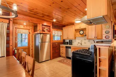 a kitchen with wooden cabinets and a stainless steel refrigerator at The Williams Cabin in Wawona