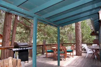 a blue pergola with a table and chairs on a deck at Hansen Cabin in Wawona