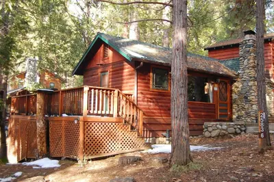 a log cabin with a large deck in the woods at Squirrel's Nest in Wawona