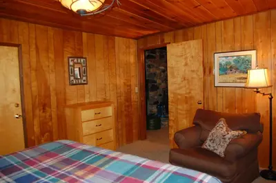 a bedroom with a bed and a chair and a lamp at Squirrel's Nest in Wawona