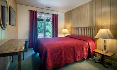 a bedroom with a bed with a red blanket and a window at River Lodge in Wawona