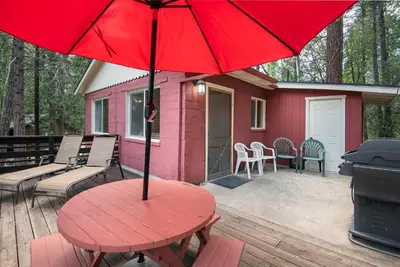 a red table on a deck with a house at Sparrow's Nest in Wawona