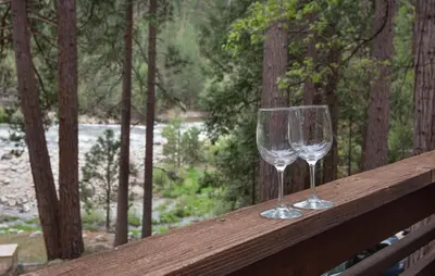 two wine glasses sitting on top of a wooden rail at Sparrow's Nest in Wawona
