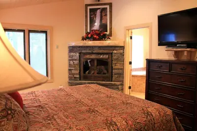 a bedroom with a fireplace with a television and a bed at Grizzly Giant in Wawona