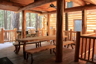 a wooden porch with a table and benches in a cabin at Grizzly Giant in Wawona