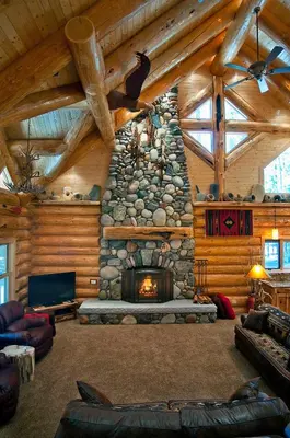 a living room with a stone fireplace in a log cabin at El Capitan in Wawona