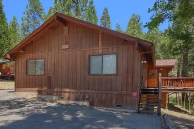 a log cabin with a staircase leading to the front door at Bordentown West in Wawona