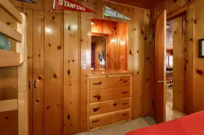 a cabin bedroom with wooden walls and a dresser at Simmons Den in Wawona