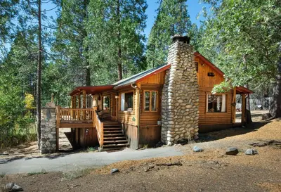 a log cabin in the woods with a stone chimney at Sequoia in Wawona