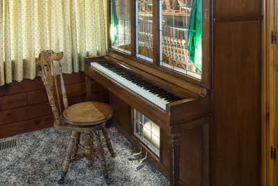 a wooden piano and a chair in a room at Sequoia in Wawona