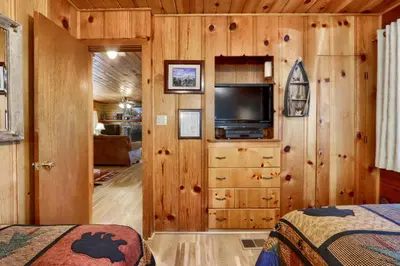 a bedroom with wooden walls and a flat screen tv at Walk-A-Bout in Wawona