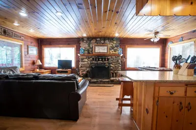 a living room with a couch and a stone fireplace at Howard's Retreat in Wawona