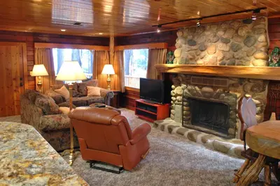 a living room with a stone fireplace and a television at Half Dome in Wawona
