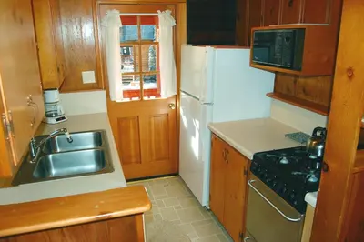 a kitchen with a sink and a white refrigerator at Nugent's Nest in Wawona