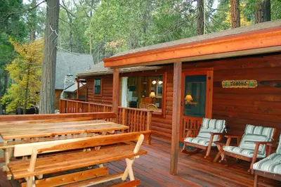 a wooden cabin with two benches on a deck at Nugent's Nest in Wawona