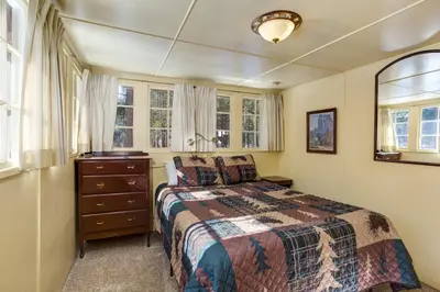 a bedroom with a bed and a dresser and windows at Chatterton's Cottage in Wawona