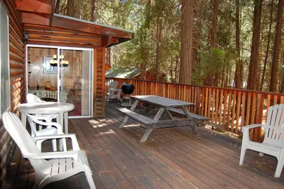 a wooden deck with a picnic table and chairs on a cabin at Shehadey's Retreat in Wawona