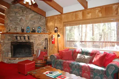 a living room with a couch and a stone fireplace at Shehadey's Retreat in Wawona