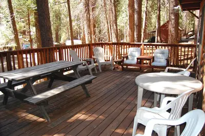 a wooden deck with a picnic table and chairs at Shehadey's Retreat in Wawona