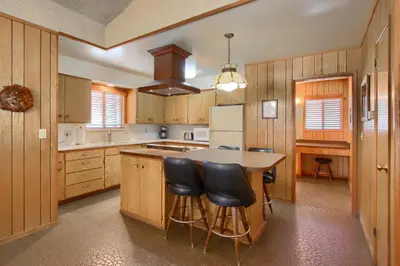 a kitchen with wooden cabinets and a island with bar stools at Hasting's Hideaway in Wawona
