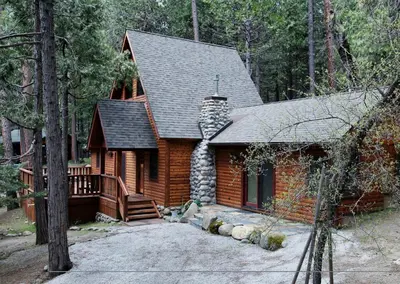 a log cabin in the woods with a porch at Boot's Haven in Wawona