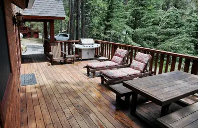 a wooden deck with chairs and a table and a grill at Boot's Haven in Wawona