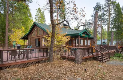 a log cabin in the woods with a porch at Deer Lodge in Wawona