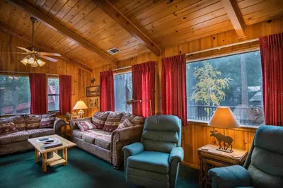 a living room with a couch and chairs and windows at Deer Lodge in Wawona
