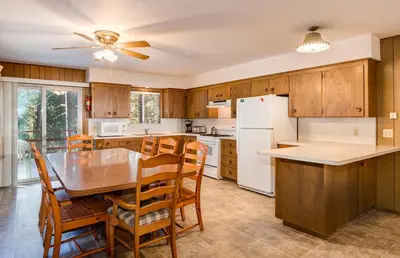 a kitchen with wooden cabinets and a table and chairs at Deer Hollow in Wawona