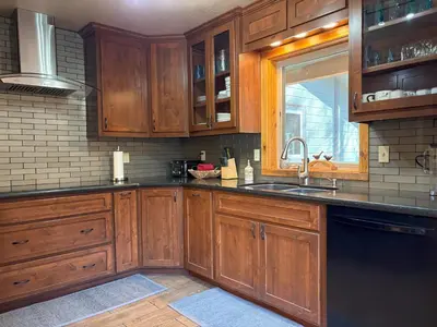 a kitchen with wooden cabinets and a sink and a window at Lily of the Valley - Big Wall, Yosemite Day Use Reservations, Breakfast, Forest View and WiFi in Yosemite West