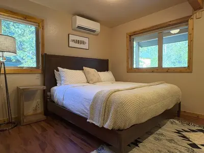 a bedroom with a bed and two windows at Lily of the Valley - Big Wall, Yosemite Day Use Reservations, Breakfast, Forest View and WiFi in Yosemite West