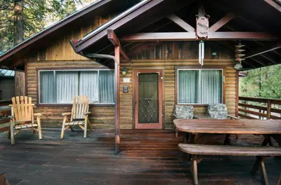 a cabin with a table and chairs on a deck at Arnetts' Cabin in Wawona