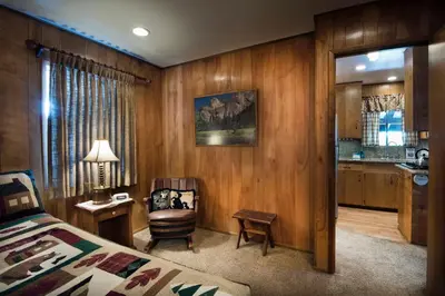 a bedroom with a bed and a chair and a kitchen at Arnetts' Cabin in Wawona
