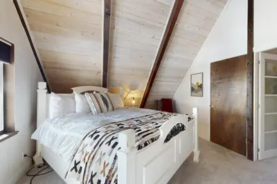 a bedroom with a white bed with a wooden wall at Sioux Serenity in South Lake Tahoe