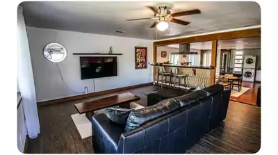 a living room with a black leather couch and a ceiling fan at Alta Peak House in Three Rivers