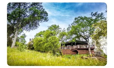 a house sitting on top of a hill with trees at Alta Peak House in Three Rivers