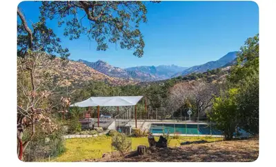 a house with a pool and mountains in the background at Alta Peak Penzion in Three Rivers