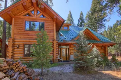 a log cabin in the woods with a porch at Yosemite's Luxury Estate at The Redwoods in Yosemite 2349 in Wawona