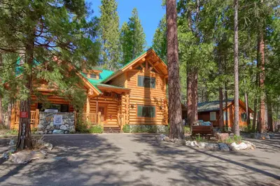 a log cabin in the woods with a driveway at Yosemite's Luxury Estate at The Redwoods in Yosemite 2349 in Wawona