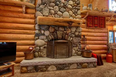 a living room with a stone fireplace in a log cabin at Yosemite's Luxury Estate at The Redwoods in Yosemite 2349 in Wawona