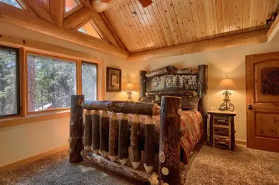 a bedroom with a wooden bed in a room with windows at Yosemite's Luxury Estate at The Redwoods in Yosemite 2349 in Wawona