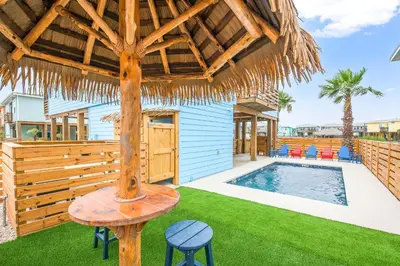 a patio with a pool and a straw umbrella at Why Knot Relax - Heated PRIVATE Pool Beach Gear Credit Included in Fresno