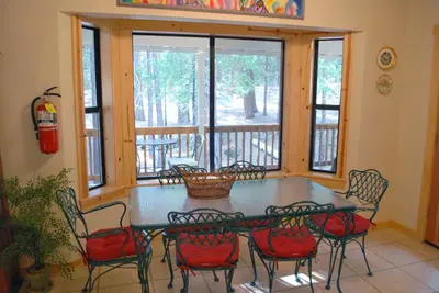 a screened in porch with a table and chairs at Doyle's Mountain in Wawona